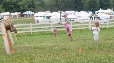 Malcolm Booze, 9, of Northshield throwing an axe during the Youth Thrown Weapons class along with Evelyn Aksim, 6, of Acre and Vicky, 5, of Aethelmearc. Children competing in Youth Thrown Weapons tournament